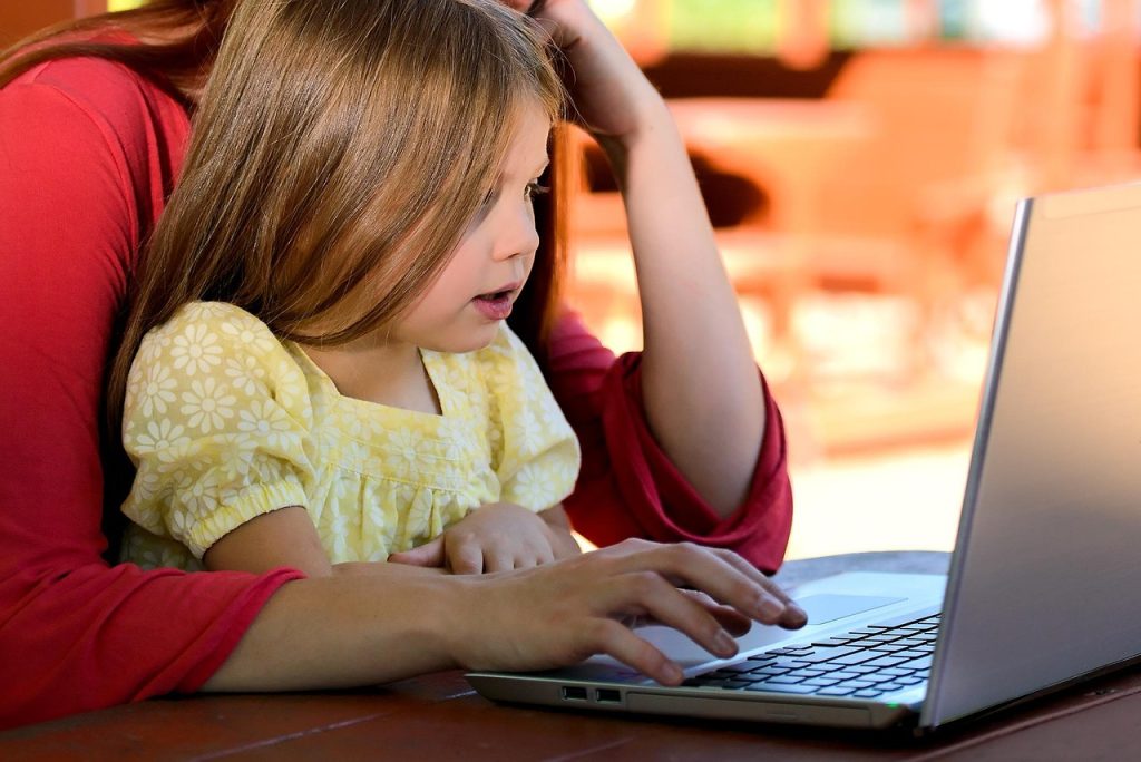 Parent with laptop at child’s sports practice] Alt text: Busy parent building a second income stream during downtime